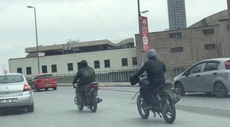 Kasksız motosikletli, yakıtı biten başka bir motosikleti iple çekti