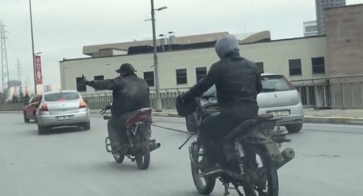 Kasksız motosikletli, yakıtı biten başka bir motosikleti iple çekti